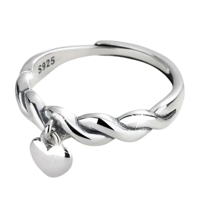 Silver ring with a twisted design and heart charm on a white background