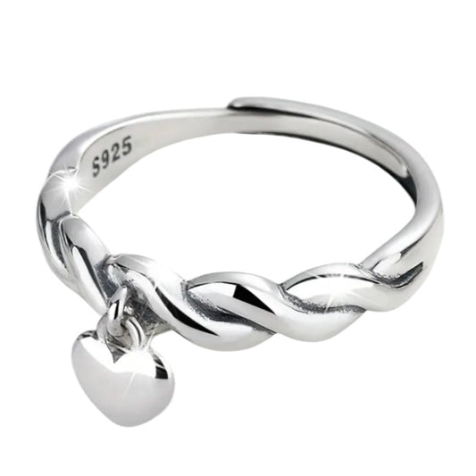 Silver ring with a twisted design and heart charm on a white background